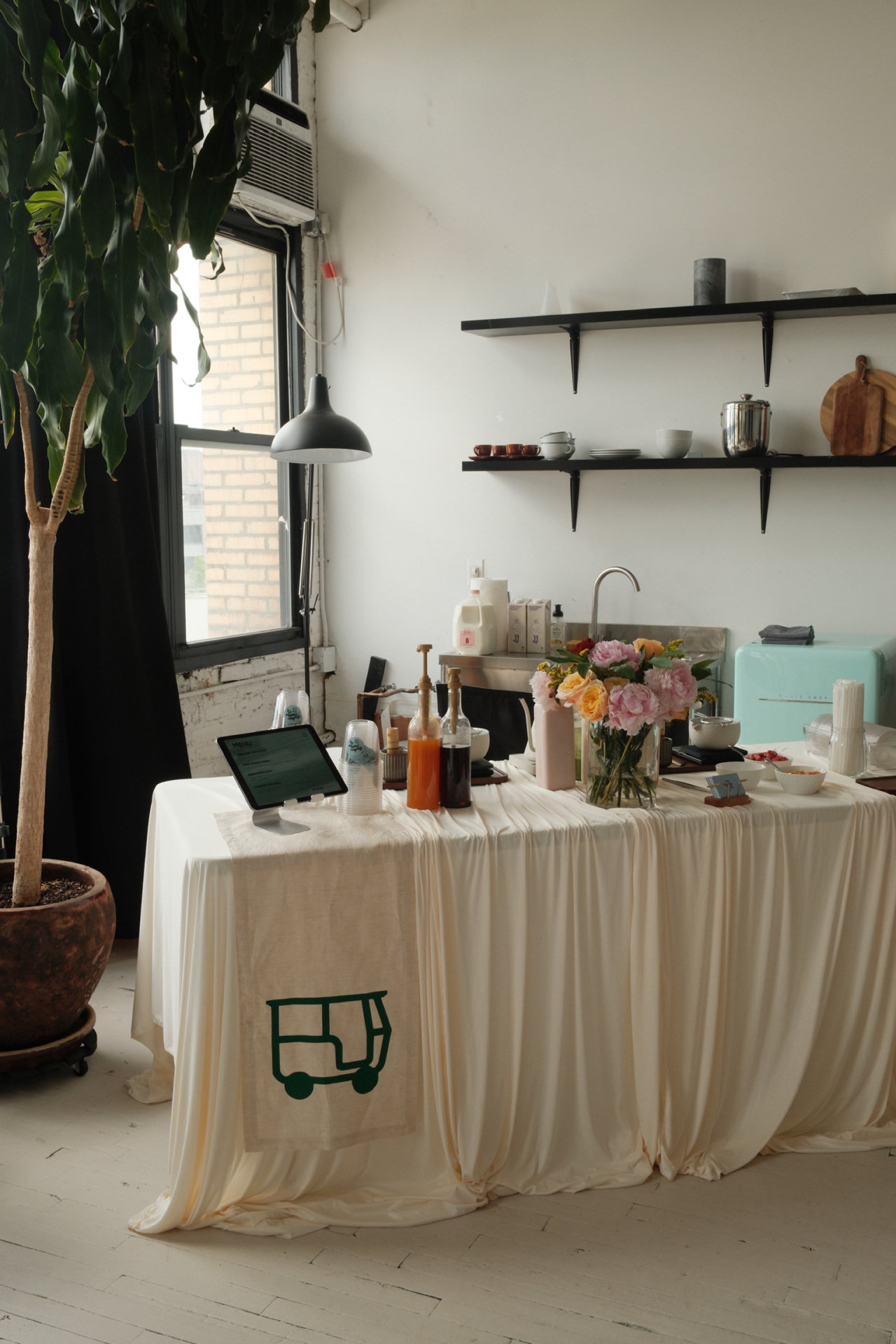 Qadeer Coffee Co beverage bar with flowers, syrups, espresso equipment, and a tablet menu