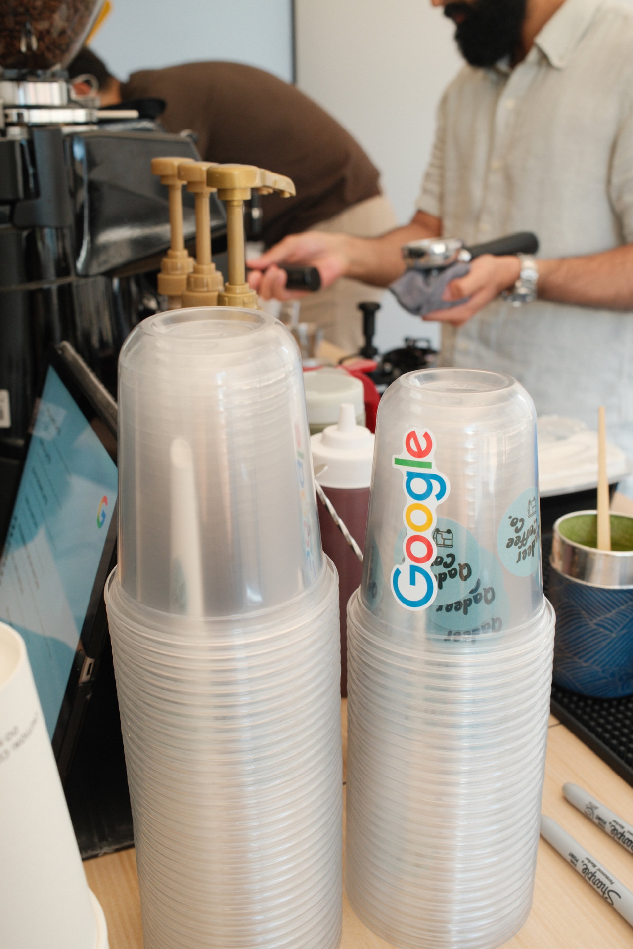Qadeer Coffee Co barista preparing drinks beside Google branded cups
